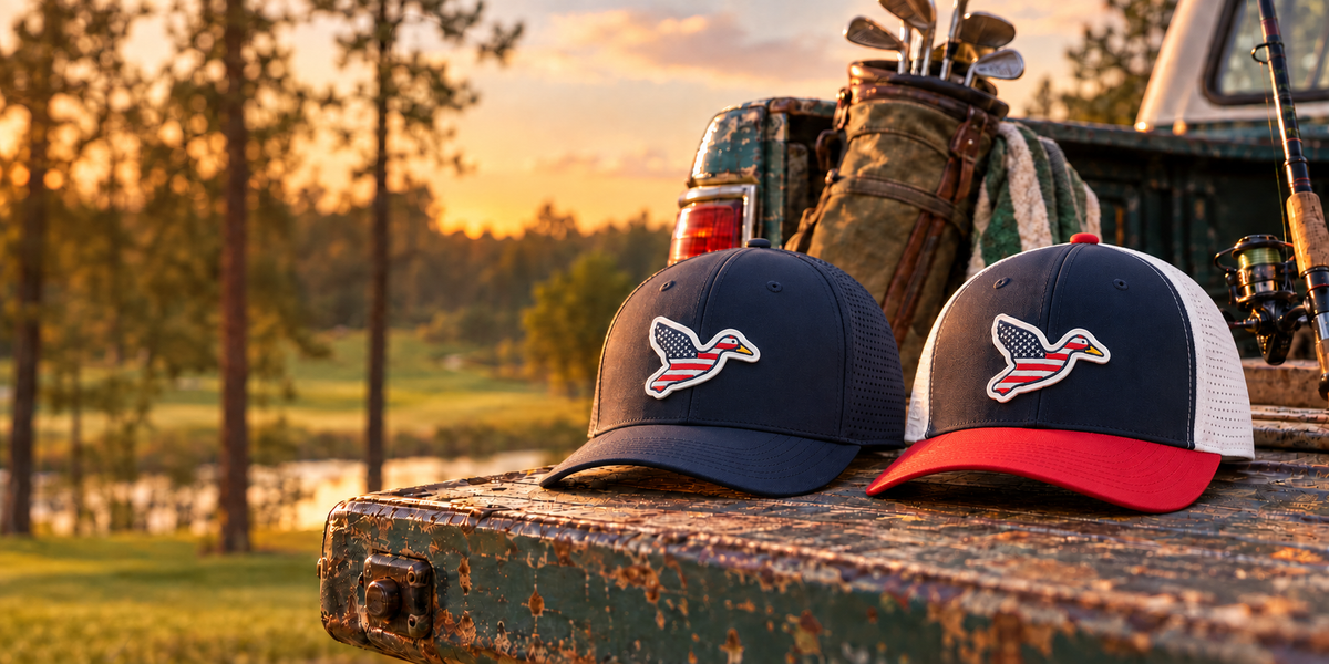 Big Duck USA flag duck performance caps in navy and red, white and blue on a truck tailgate at sunset